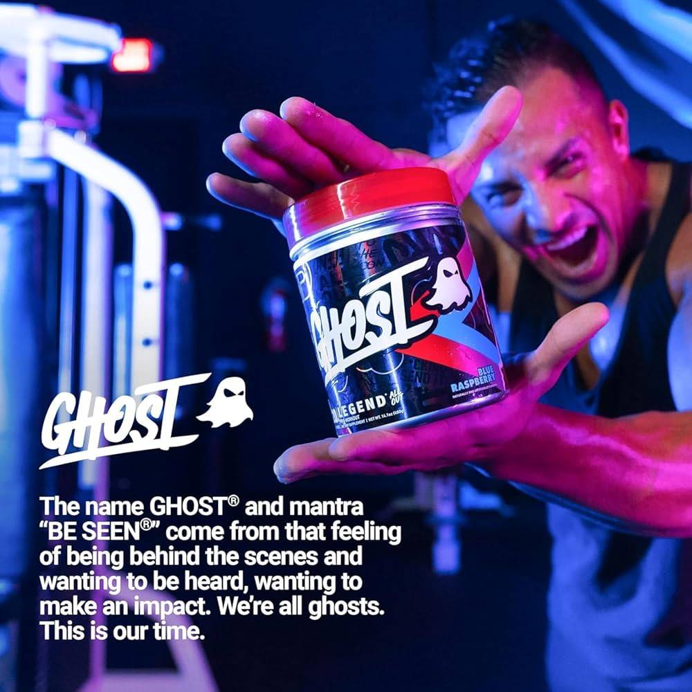 Man holding Ghost Legend All Out Pre Workout Blue Raspberry tub in gym setting. Promotes energy, performance, and motivation with 400mg caffeine.