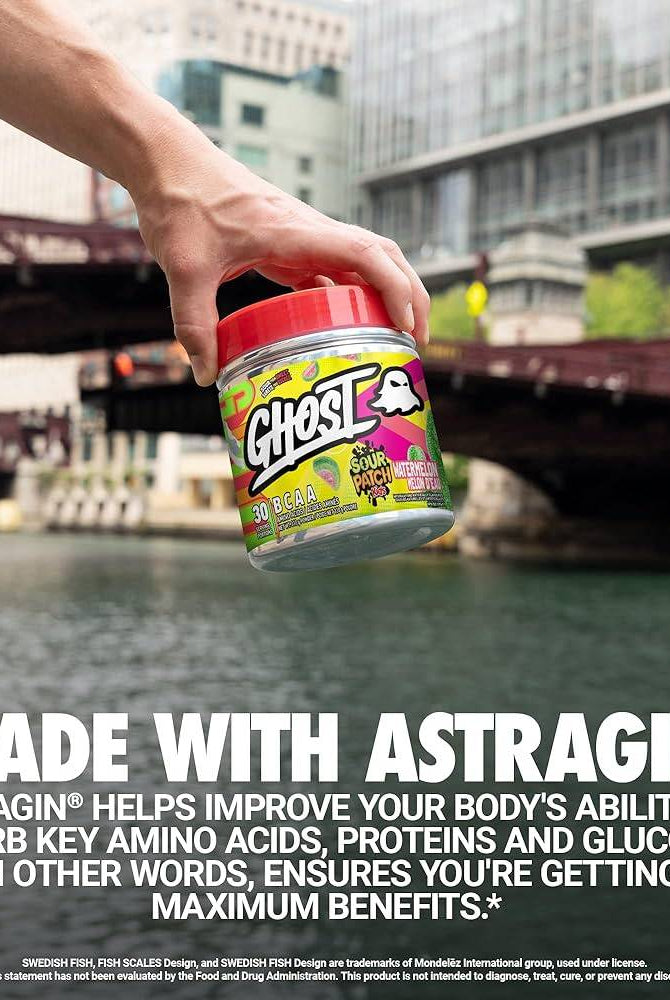Hand holding GHOST BCAAs Sour Patch Kids Redberry tub near water, highlighting Astragin® benefits for amino acid absorption.