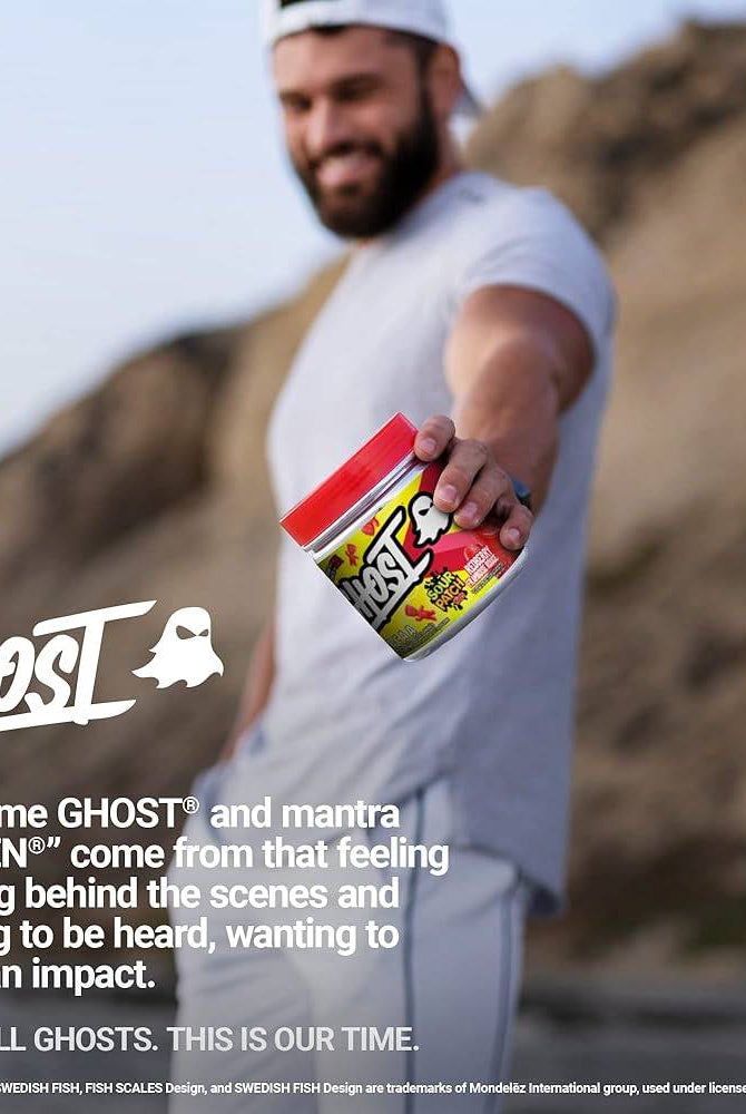Man holding GHOST BCAAs Sour Patch Kids Watermelon tub outdoors, promoting the brand's fitness supplement lifestyle message.