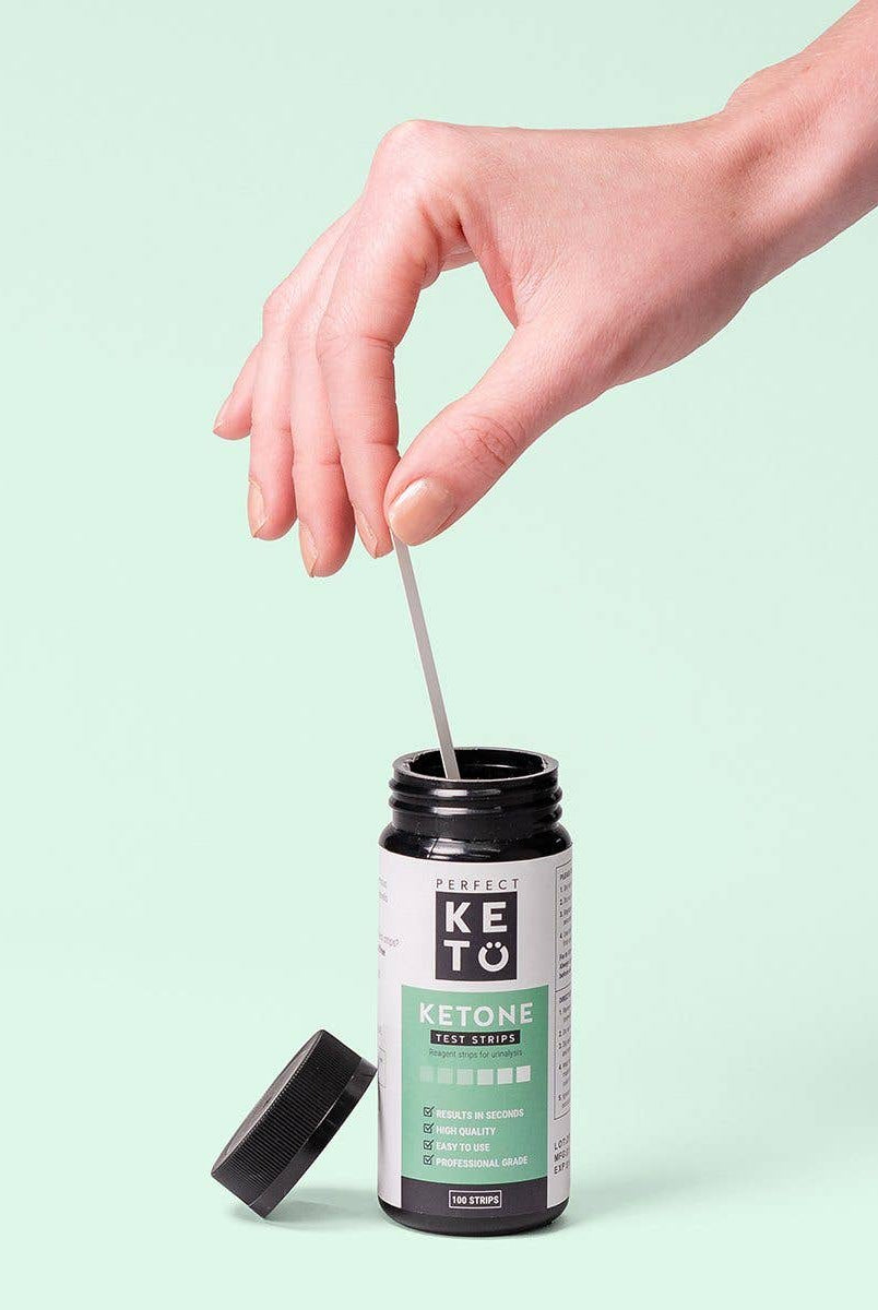 Hand dipping strip into Perfect Keto Ketone Test Strips bottle. Simple and fast keto progress testing for diet monitoring.