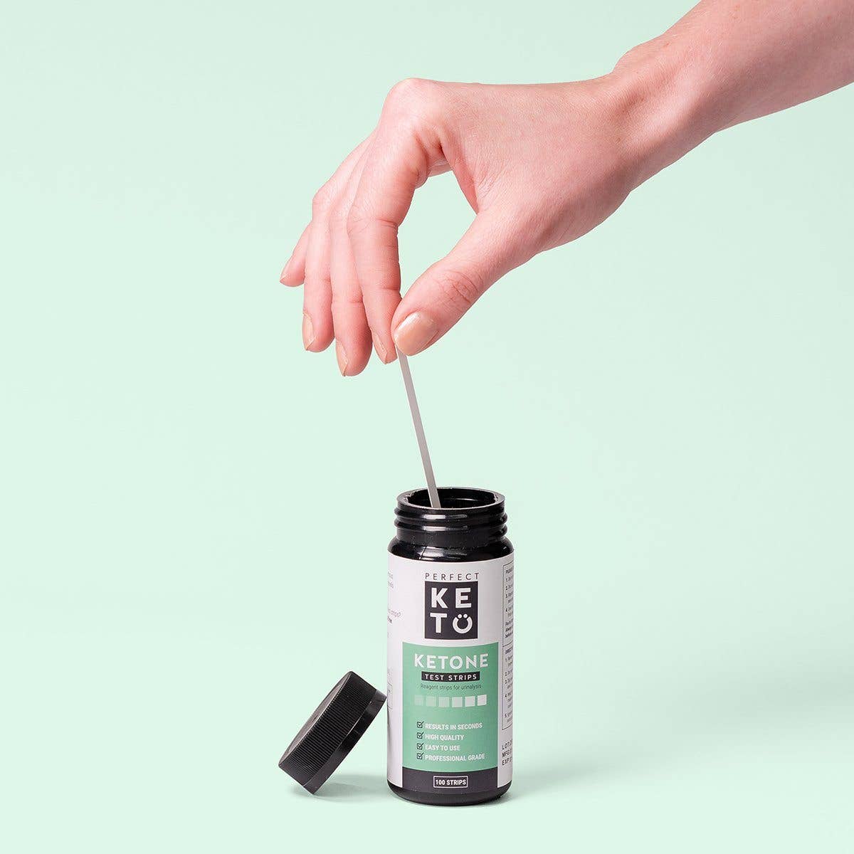 Hand dipping strip into Perfect Keto Ketone Test Strips bottle. Simple and fast keto progress testing for diet monitoring.