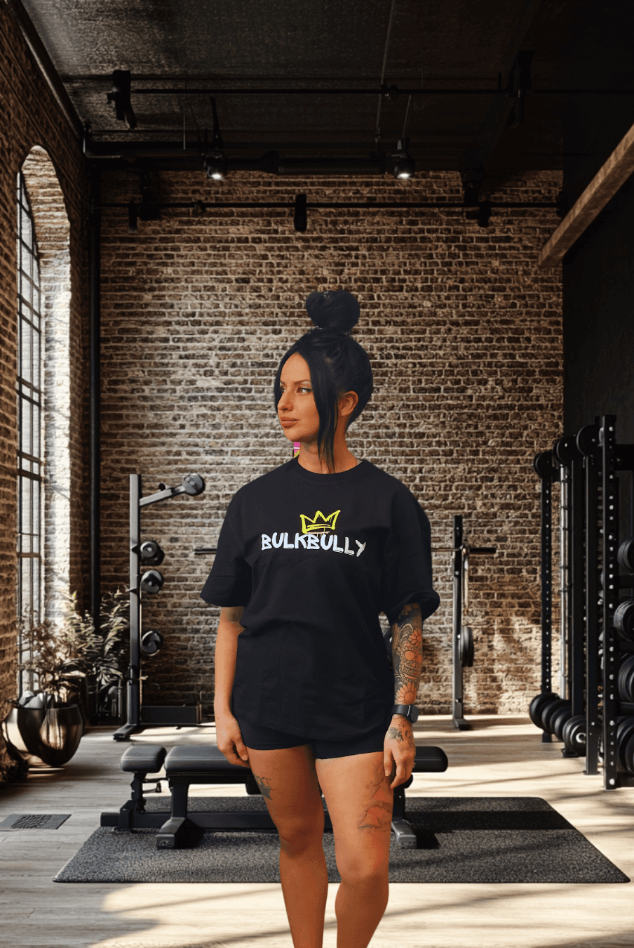 BulkBully G.O.A.L.S Collection Women's Black Oversized Tee featuring bold front logo, styled in a modern gym setting for activewear appeal.
