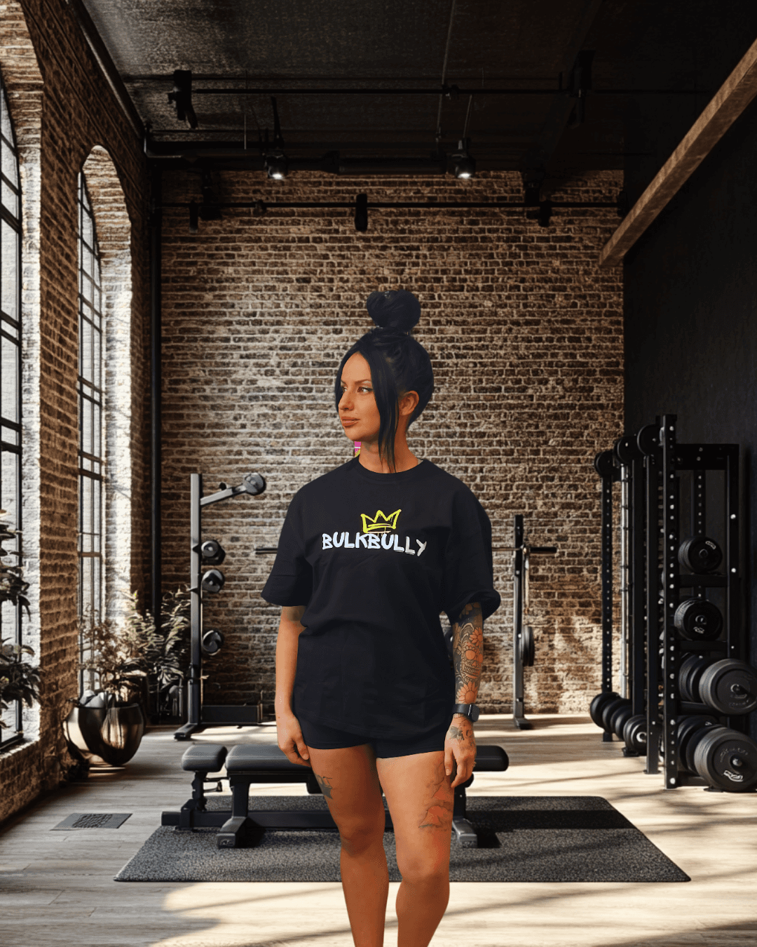 BulkBully G.O.A.L.S Collection Women's Black Oversized Tee featuring bold front logo, styled in a modern gym setting for activewear appeal.